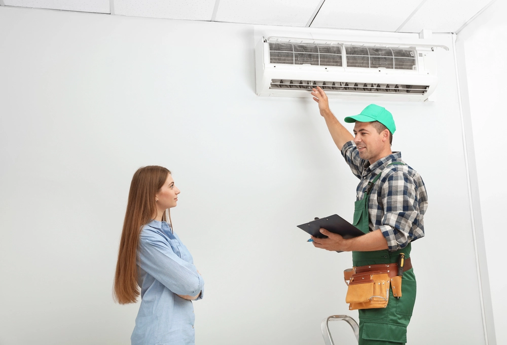 Home 2 An image of an HVAC technician explaining a wall-mounted AC unit to a homeowner during an inspection.